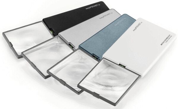 The image shows a black, flat reading magnifier with a transparent magnifying glass on one side. The magnifier is lightweight and portable, with an integrated light source.