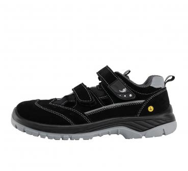 The image shows a black children's shoe made of suede with two Velcro straps. The sole is gray and provides a sturdy, non-slip surface. The shoe has a sporty shape.