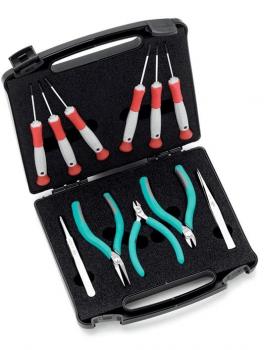 The image shows an open toolbox with black foam. Inside, there are various tools: four small screwdrivers with red handles, three pliers, and fine tweezers with colored handles.