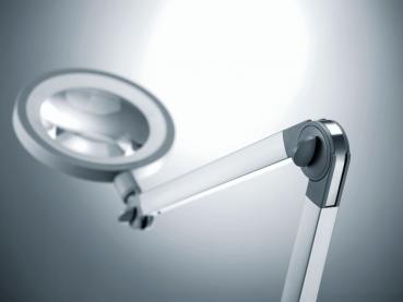 The image shows a modern light arm with a large, round lamp. The arm is swivelable and made of silver metal, with a clear, focused light inside the lamp.