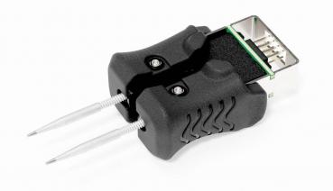 The image shows a black tool with two long, thin tips. It has an oval shape and a built-in connector on top that can be attached to an electrical device.