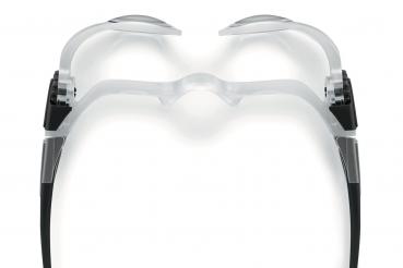 The image shows a transparent pair of glasses with a modern, minimalist design. The lenses are slightly curved and the arms are black. The shape appears futuristic and elegant.