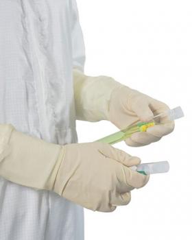 In the picture, there are two sample tubes in one hand, while the other hand is holding a green tube. The person is wearing beige gloves and a white coat.