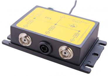 The image shows a rectangular black casing with several ports: two round sockets on the left and one central socket. The top is yellow and displays technical labels.