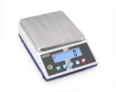 The image shows a digital scale with a smooth, rectangular metal surface. Below it, there is a display with blue digits and several buttons for operation.