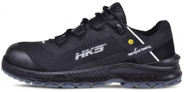 Der Schuh ist ein leichter, schwarzer Sportschuh mit einem luftigen Obermaterial. Er hat eine schwarze Sohle und ein schlichtes Design mit einem weißen Streifen und einem gelben Logo.