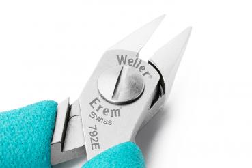 The image shows a precise pair of pliers with two pointed blades and a central turning knob. The handle is turquoise, and the blades are made of shiny metal.