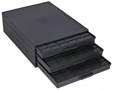 Das Bild zeigt eine schwarze, flache Box mit drei herausziehbaren Schubladen. Jede Schublade hat Fächer, um kleine Objekte zu organisieren. Die Oberfläche ist glatt und unauffällig.