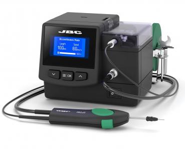 The image displays a compact device with a screen and buttons. It has a black casing and a green surface. On one side, a tool with a fine tip is attached.