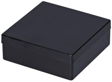 Das Bild zeigt eine quadratische, schwarze Box. Sie hat einen flachen Deckel und eine glatte Oberfläche, die glänzend wirkt. Die Kanten sind rechtwinklig und die Box steht stabil.