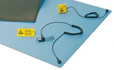The image shows a blue mat with a gray pillow, a yellow warning sign, and a connecting cable. A microphone is integrated into the cable and connected.