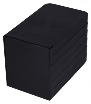 Das Bild zeigt eine rechteckige, schwarze Box. Sie hat eine matte Oberfläche und besteht aus mehreren übereinander gestapelten, flachen Elementen. Die Ecken sind abgerundet.