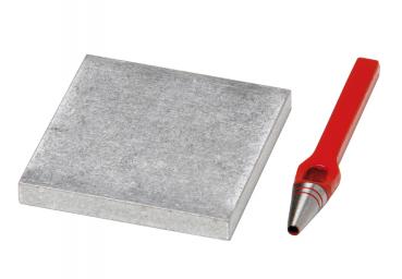 In the picture, there is a gray, square piece of metal and a red pencil with a pointed tip. The contrast between the smooth metal and the colored pencil is striking.