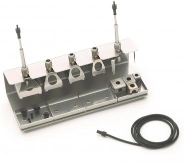 The image shows a metallic tool set with several holders and connections. There are three upright elements and a cable connection that runs sideways. The surface is flat.