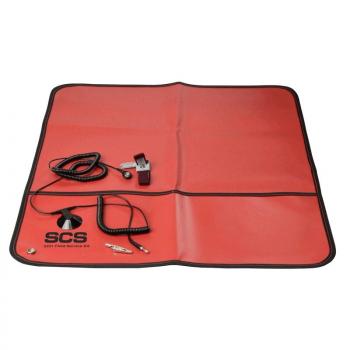 The image shows a red, rectangular mat with a black border. On it are several cables and a small gray clip. It is a kind of pad for technical devices.