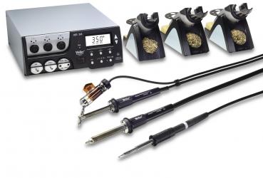The image displays a soldering iron kit with a control unit and several soldering tips. The control unit features a digital display and multiple controls. Everything is arranged on a smooth surface.
