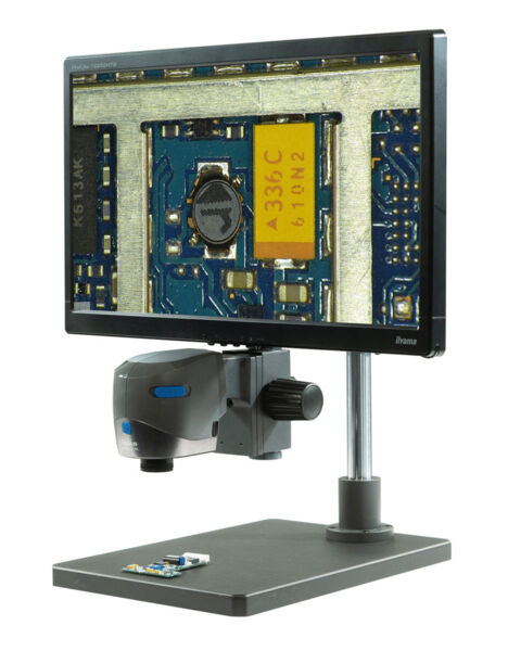 The image shows a microscope with a gray lens and a white stand. It has a slide holder and is sleek and modern in shape.