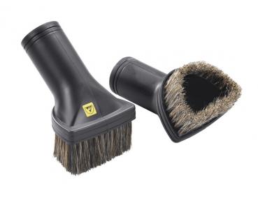 The image shows two brushes with black handles. One brush has a wide, flat head, while the other is wedge-shaped and narrow. Both have soft bristles.