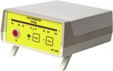 The image shows an electrometer with a yellow front panel. It features controls and displays for the voltage. It has a red connector and stands on two small feet.