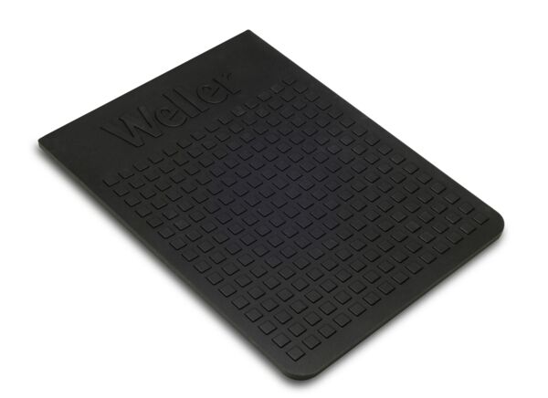 The image shows a rectangular, black mat with a grippy surface. It has a textured surface with small square bumps and bears the inscription 