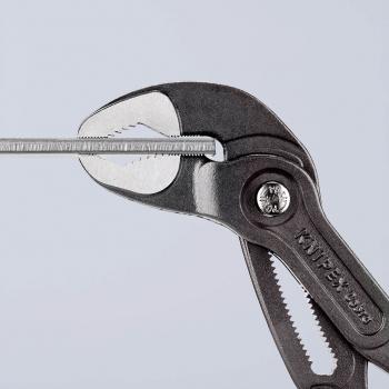 Das Bild zeigt eine Zange aus Metall mit einer rautenförmigen Greiffläche. Sie hält einen schmalen, geraden Gegenstand in der Mitte. Der Hintergrund ist einfarbig hell.