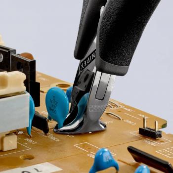 Auf einer Leiterplatte sind blaue elektronische Bauteile zu sehen. Eine Zange greift ein Bauteil. Der Hintergrund ist hell, die Zange hat schwarze Griffe.