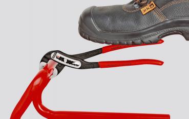 A black safety shoe is standing on a red pair of pliers. The pliers have a black, shiny head and red handles that are pressed together while the shoe is on top.