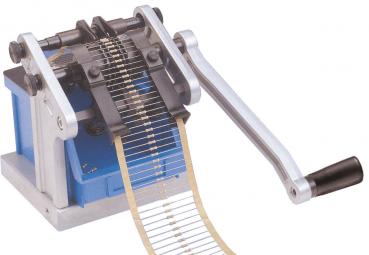 The image shows a mechanical machine with a sturdy frame and a long metal band that is pulled through a mechanism. A handle on the side is used to operate the machine.
