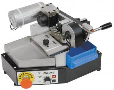The image shows a compact machine setup with an engine and various mechanical parts. It has buttons and an emergency stop area, as well as a workspace on the left side.