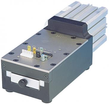The image shows a compact device with a rectangular casing. It has a metal surface, cooling fins on the top, and a front with a slider and multiple ports.