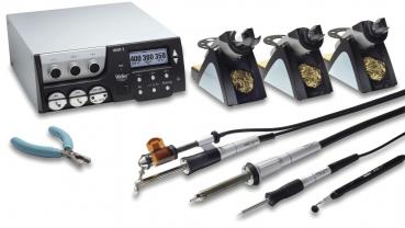 The image shows a soldering device with a digital control panel and several soldering tips. Next to it are pliers and cables. The entire setup is intended for soldering work in electronics.