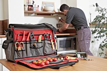 The image displays a tool bag with red lining. Inside, there are several yellow screwdrivers, a saw, pliers, and various accessories. The bag is open and neatly organized.