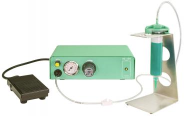 The image shows a medical device in soft green tones. It has a pressure gauge and a rotary knob. Next to the device, there is a foot pedal and a container on a metal stand.