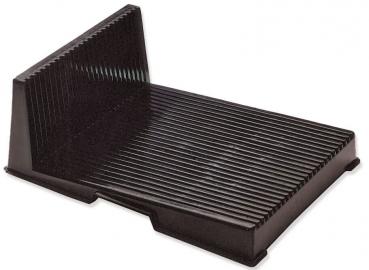 The image shows a black, rectangular object with a slanted back wall. The surface is ridged, giving it texture. It is often used as a stand or holder.