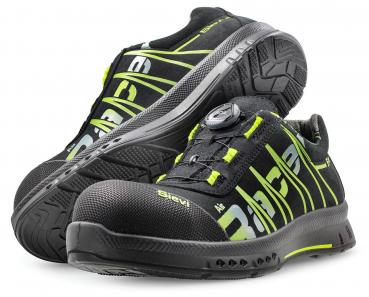 The image shows a pair of black work or sports shoes with green accents. They feature a sturdy rubber sole and an innovative quick-lace system.