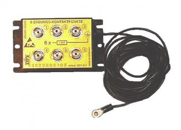 The image shows a yellow junction box with six ground contact points, which have round metal openings. A black cable is attached to it, leading to a flat connection plate.