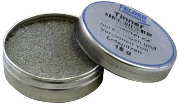 The image shows a round, metal tin with a screwable lid. The tin is partially open and contains gray, fine material. The lid reads 
