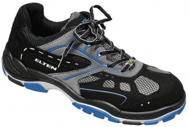 Der Schuh ist sportlich und in Schwarz mit grauen und blauen Akzenten. Er hat eine atmungsaktive Oberfläche, verstärkte Seiten und eine rutschfeste Sohle. Die Schnürsenkel sind gut sichtbar.