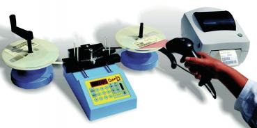 The image shows a white label printer with a glossy lid and a green button. Next to it is a roll of white labels that is being unrolled.