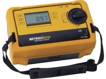 The image displays a compact, rectangular measuring device in bright yellow with a digital display and a large rotary knob. There are several buttons and a carrying strap on the side.