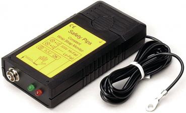 The image shows a black security device with yellow labeling. It has a connection on the front, two colored LEDs (red and green), and a cable leading out from the side.