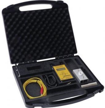 The image shows a black suitcase that is open. Inside, there are various technical devices, including a yellow measuring device, cables, and a small metal component, all neatly arranged.
