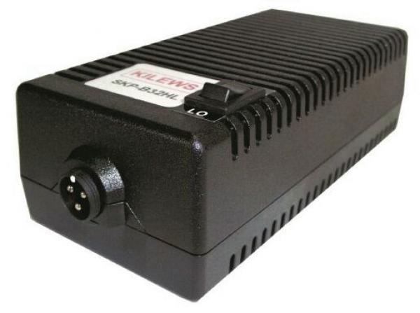 The image displays a black, rectangular device with a ribbed structure on the top. On one side, there is a circular connector and a small switch. It has a slight elevation in the middle.