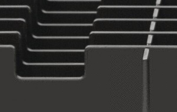 The image shows a close-up of a black, textured material with parallel grooves and sharp corners. The surface appears smooth and orderly.