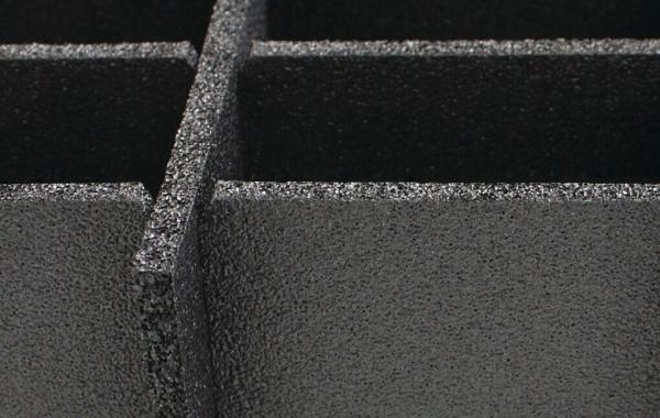 Das Bild zeigt eine schwarze, strukturierte Oberfläche mit mehreren rechteckigen Vertiefungen. Die Kanten sind deutlich abgetrennt, was ein Gefühl von Tiefe und Dimension vermittelt.