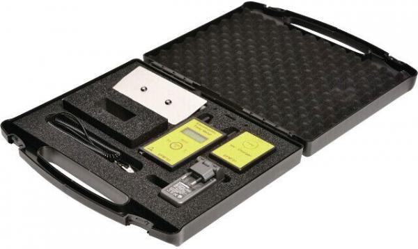 The image shows an open, black-foaming suitcase. Inside, there are various devices and accessories, including a digital display, cables, and other technical components.