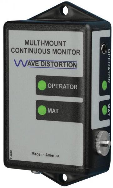 The image displays a rectangular device with a gray front. It has two green light indicators for "OPERATOR" and "MAT" as well as a rotary knob at the bottom. The text is arranged in two lines.
