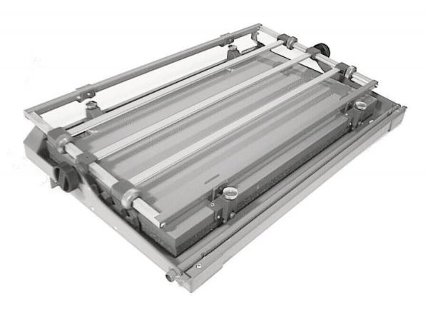 The image shows a flat, rectangular table with metallic elements and narrow grooves. It is foldable, making it portable and space-saving.
