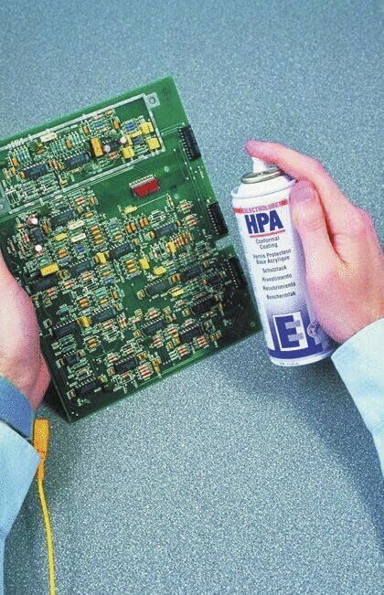 Das Bild zeigt eine Person, die eine grüne Leiterplatte in der einen Hand und eine Sprühdose mit Elektronikreiniger in der anderen Hand hält. Der Hintergrund ist grau und strukturiert.