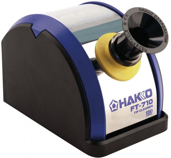 The image displays an electric tip cleaner. It features a rounded black base, a transparent lid, and a circular opening with a yellow border. The brand "HAKKO FT-710" is visible.